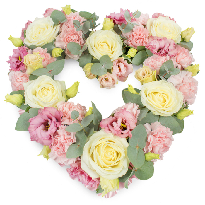 In this image, a lush, heart-shaped floral arrangement takes centre stage, its pastel blossoms standing crisp and clear against a stark white background. The heart is densely packed, with no bare gaps, giving a sense of completeness and unwavering affection. Large creamy yellow and ivory roses are placed at balanced intervals, their petals arranged in neat spirals that open into full, rounded blooms, conveying a sense of gentle dignity. Between these, light pink carnations are tightly clustered, their frilled, ruffled petals adding a downy softness and making the heart appear almost cushioned. Deeper magenta-pink and soft mauve lisianthus are nestled among the lighter tones, their slightly trumpet-shaped flowers and occasionally darker centres lending contrast and visual depth, much like the complex emotions felt during times of mourning. Silvery-green eucalyptus foliage winds throughout the wreath, framing the outer edges of the heart and slipping toward the centre, its rounded leaves and matte surface providing both structure and a calming, natural element. Small, tightly furled yellow-green buds are dotted through the arrangement, subtle signs of life and renewal. The light in the photograph is even and diffused, highlighting each flower's texture without glare or harsh shadow. As a design, it feels perfectly suited to West Drayton's blend of village life and nearby waterways, something you might imagine being delivered by Florist West Drayton to a service near the High Street or a quiet home gathering to honour a loved one. This heart-shaped wreath is an ideal funeral or sympathy tribute, expressing love, remembrance, and quiet support to families in and around West Drayton.